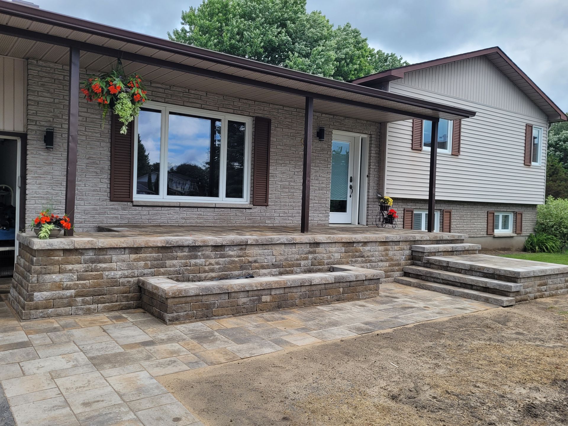 Brick house exterior with porch, stone steps, and flower boxes.