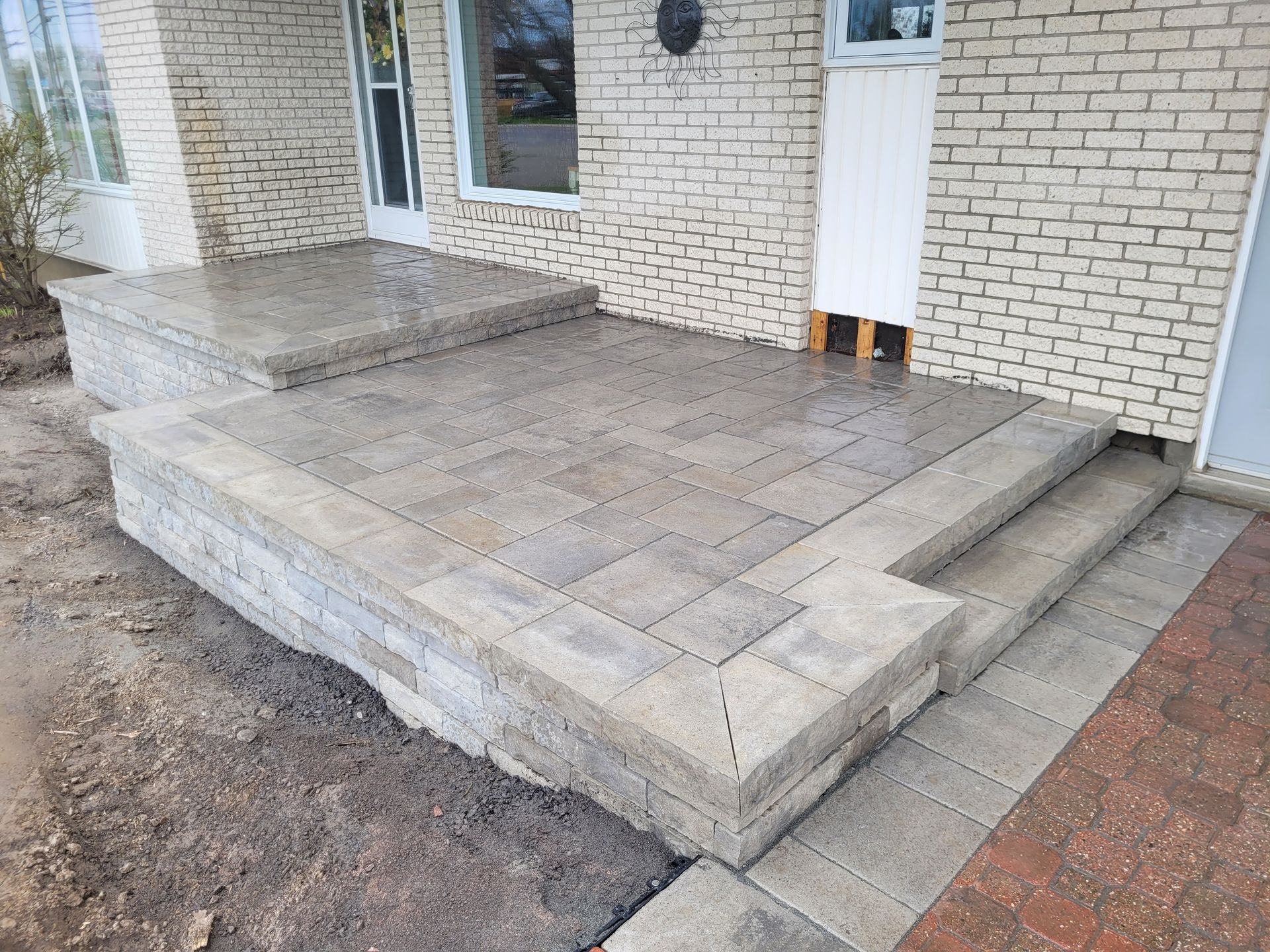 Brick patio and steps leading up to a brick-walled house.