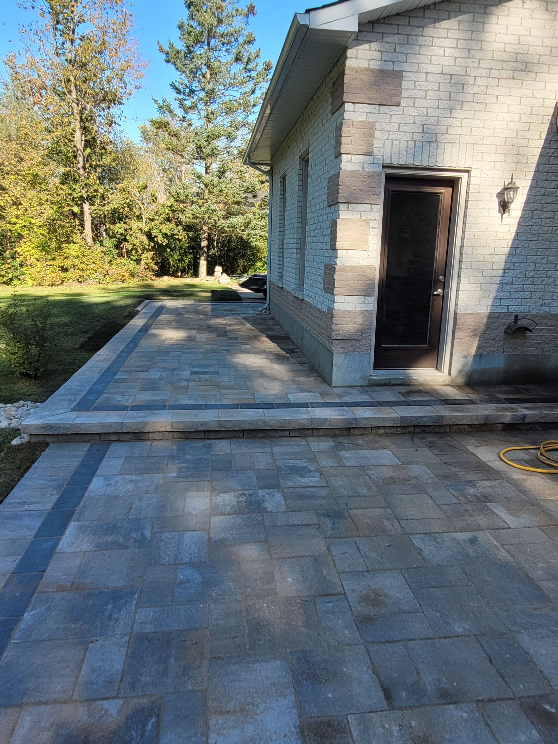 Stone patio with a raised edge, leading to a building entrance.