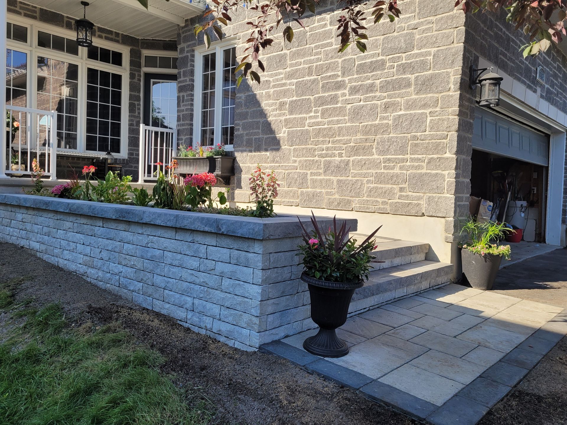 Stone facade home with flower beds, steps, and a garage.