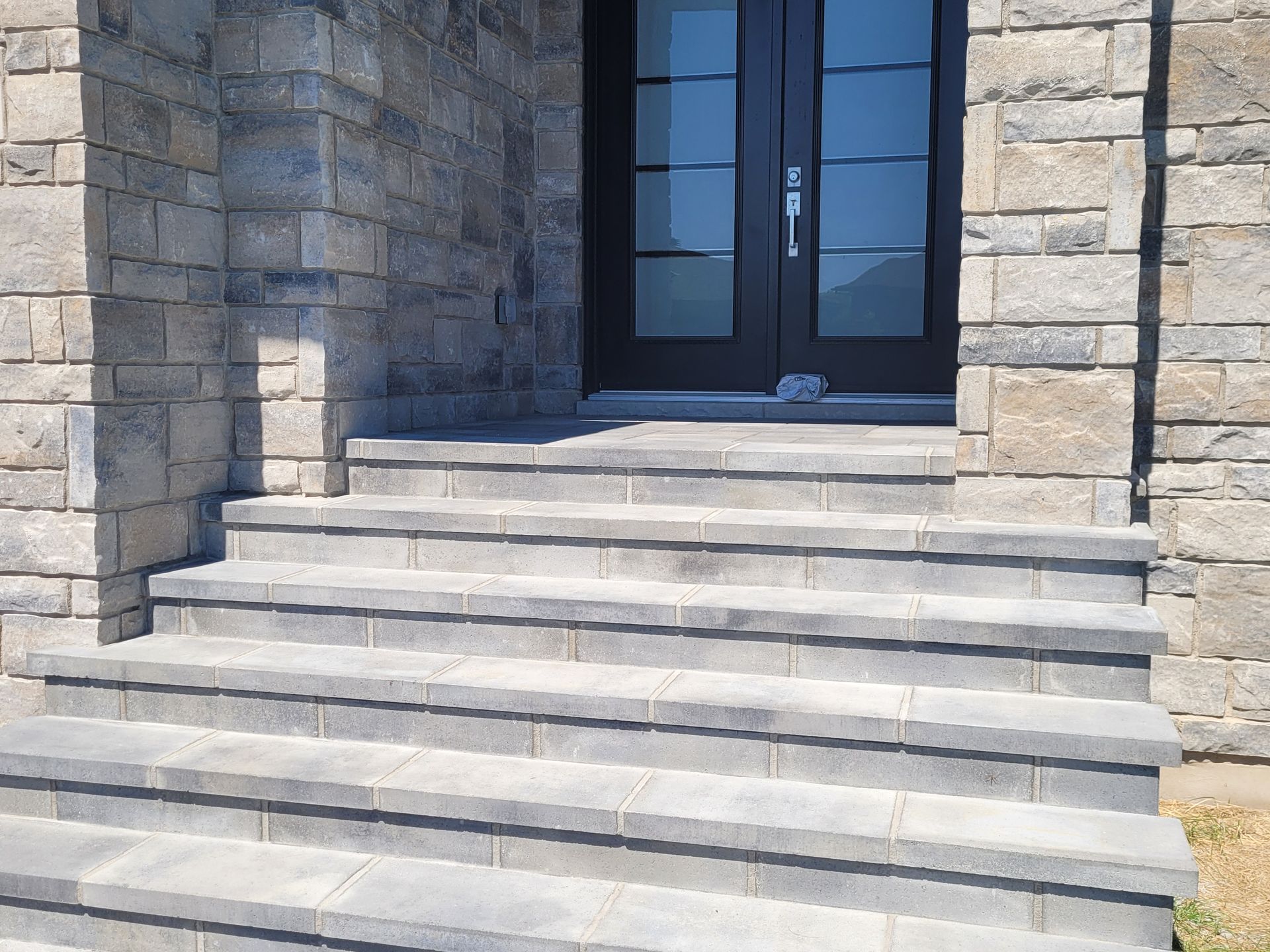 Gray stone steps leading to a dark door, flanked by stone walls.