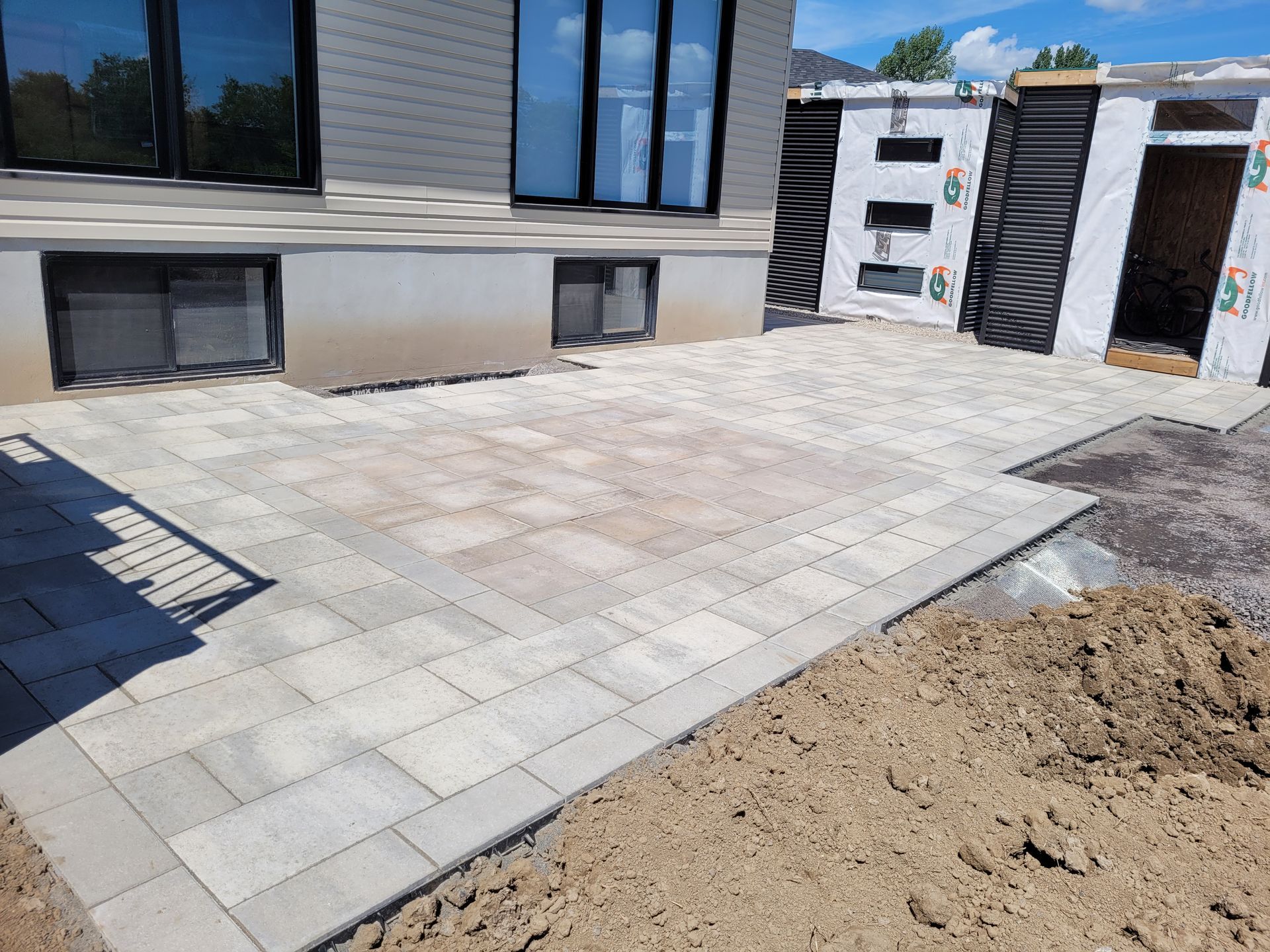 Paver patio outside a modern home, light gray and tan blocks.