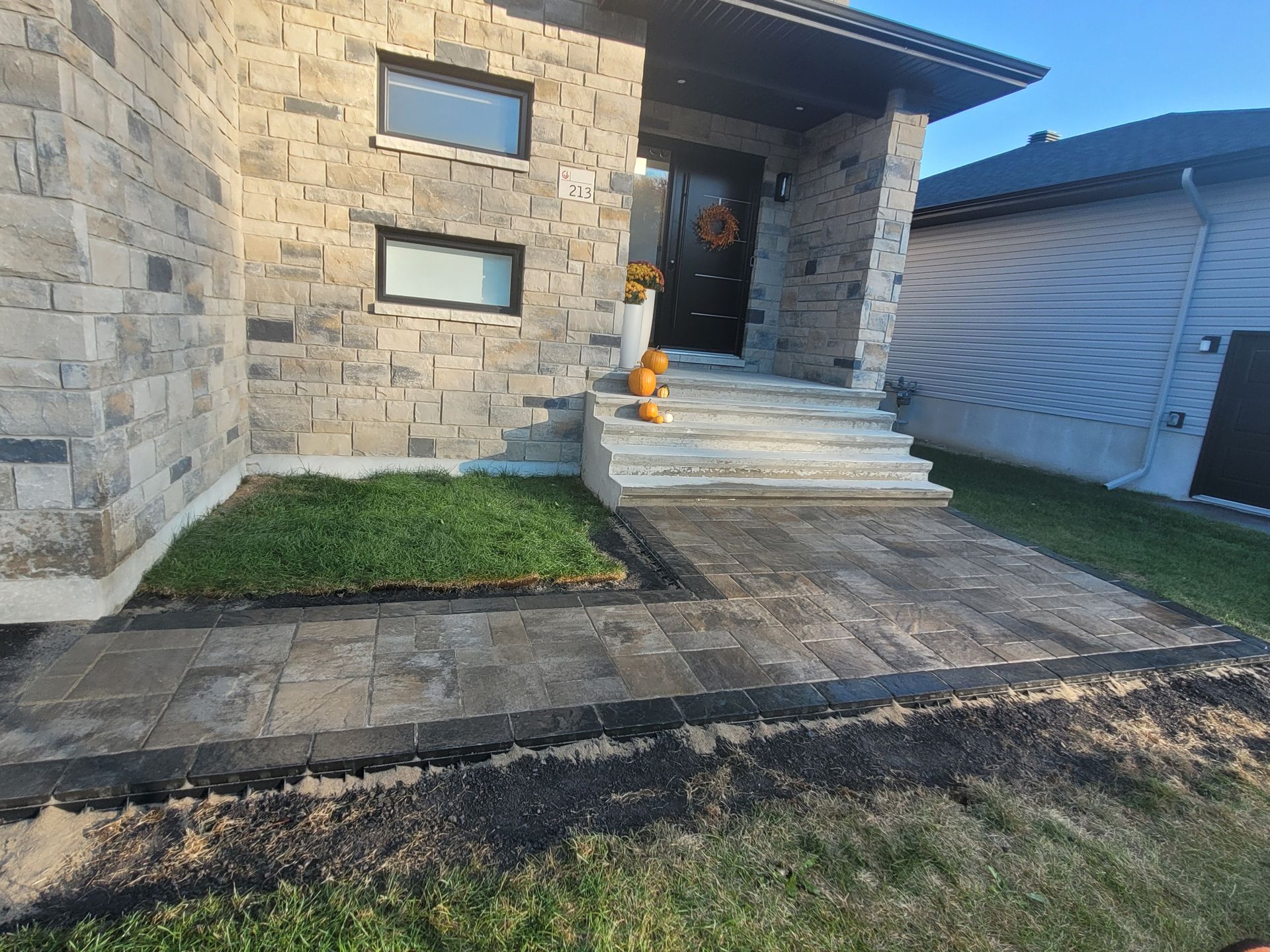 Stone house exterior with stone steps, walkway, small lawn, and dark door.