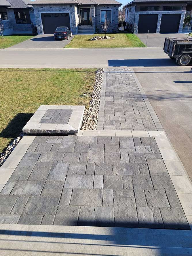 Stone walkway with integrated steps and landscaping, leading to houses in a suburban setting.