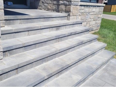 Gray stone steps leading up to a building entrance with stone facade.