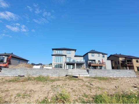 New houses under construction on a sunny day. Gray homes with retaining walls.