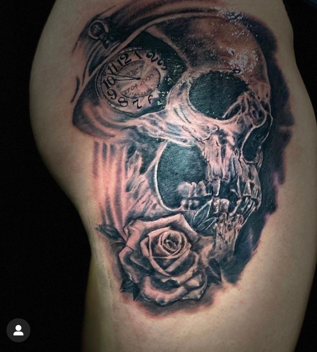 Ein Tattoo eines Totenkopfes mit einer Rose und einer Taschenuhr