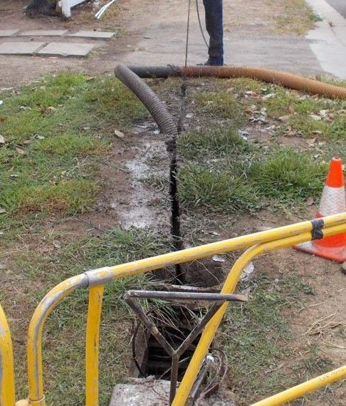 A White Orange Pipe Is Down A Crack In Some Grass — Porta-Vac in Bowen, QLD