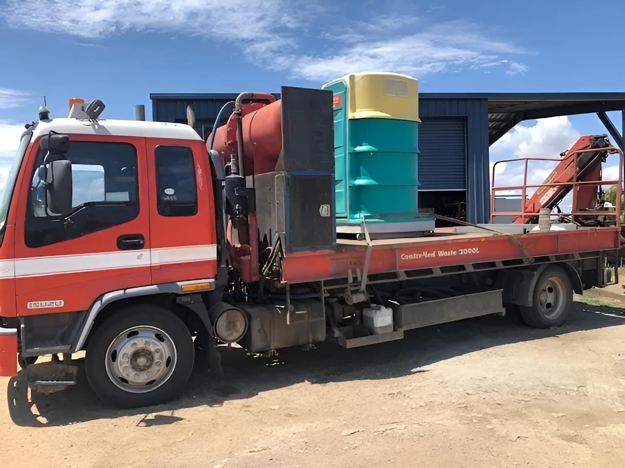 A Red Truck With a Crane on the Back is Parked in Front of a Building — Porta-Vac in Bowen, QLD