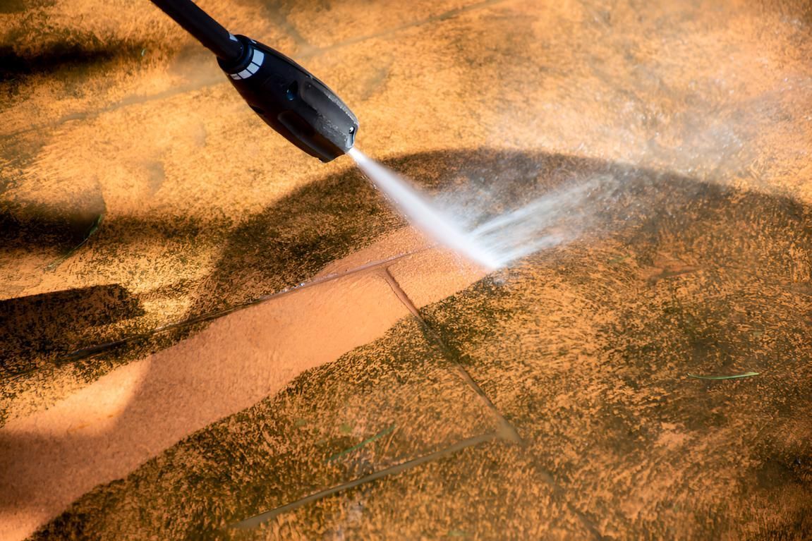 A Person Is Using A High Pressure Washer To Clean A Concrete Floor — Porta-Vac in Bowen, QLD