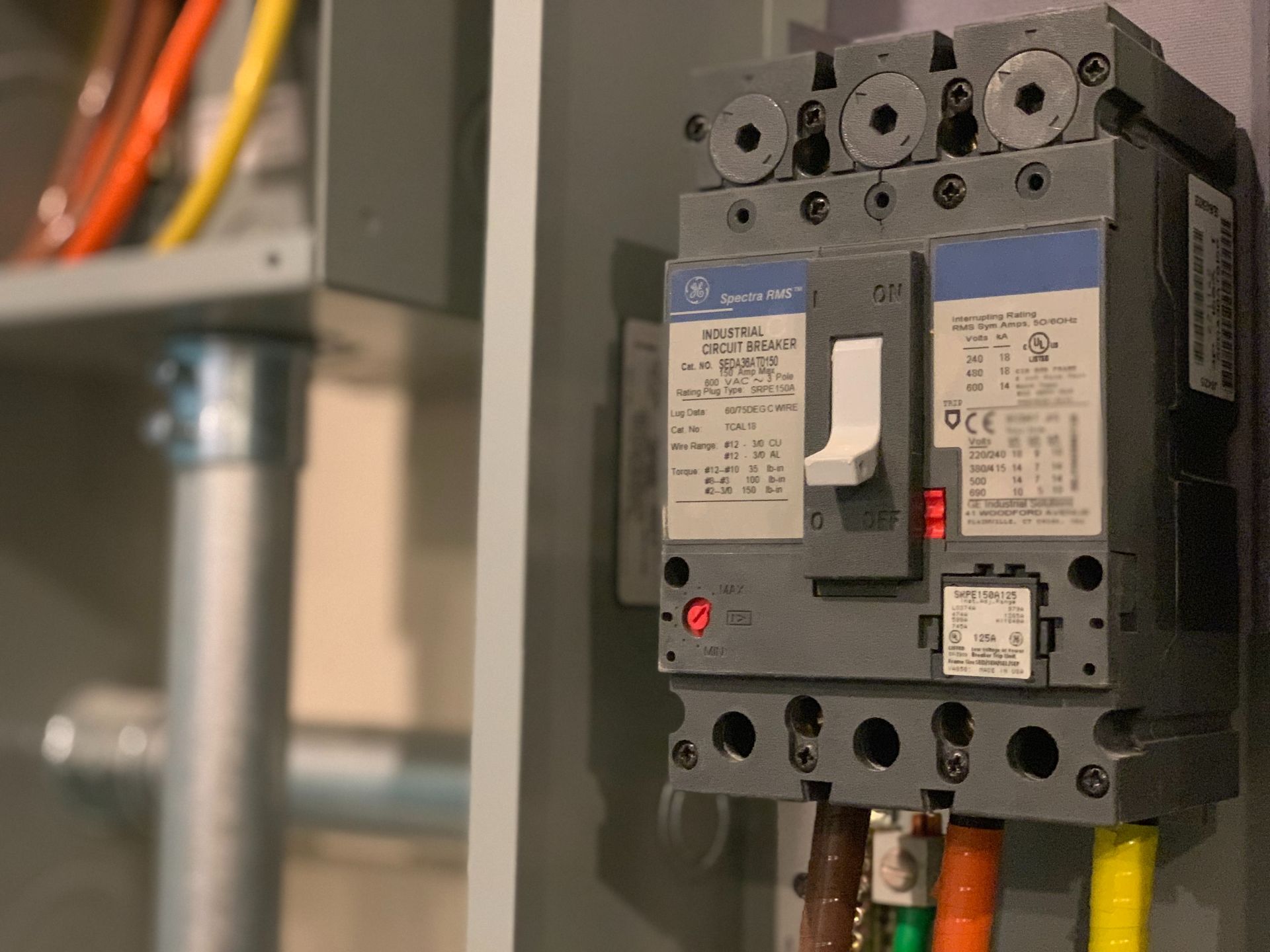 Close-up of a breaker in an electrical panel with exposed wires.