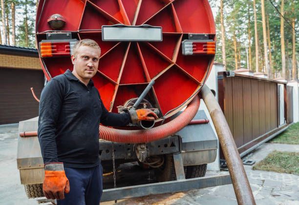 Man with black sweater and gloves is standing next to sewer pumping machine