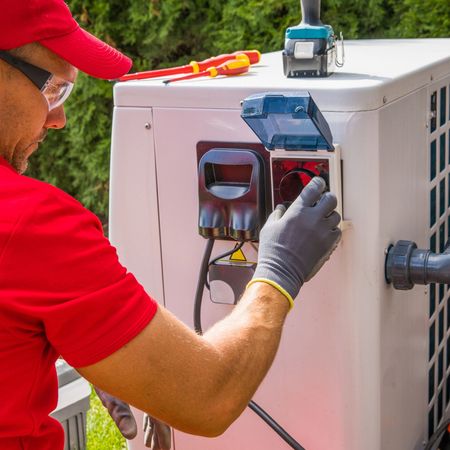 A man in a red shirt is working on an air conditioner.