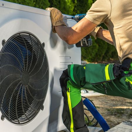 A man is working on a fan with a drill