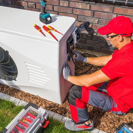 A man in a red shirt is working on a white box.