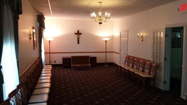 Interior of a funeral home chapel with chairs, cross, and decorative lighting.