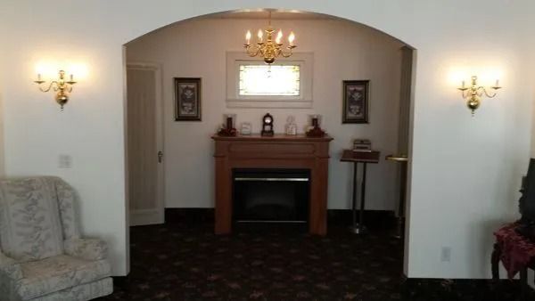 Interior room with fireplace, chandeliers, sconces, and furniture.