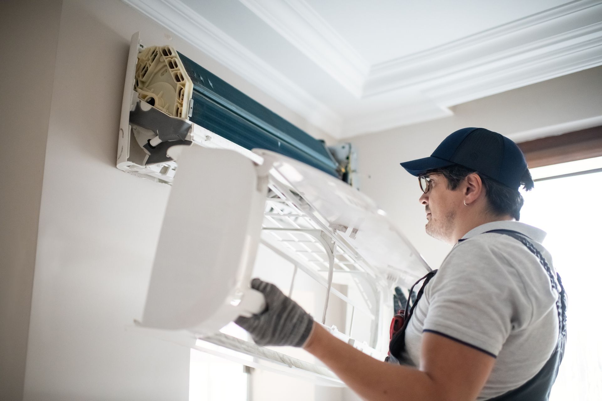 Technician cleaning AC coils and inspecting parts during maintenance.