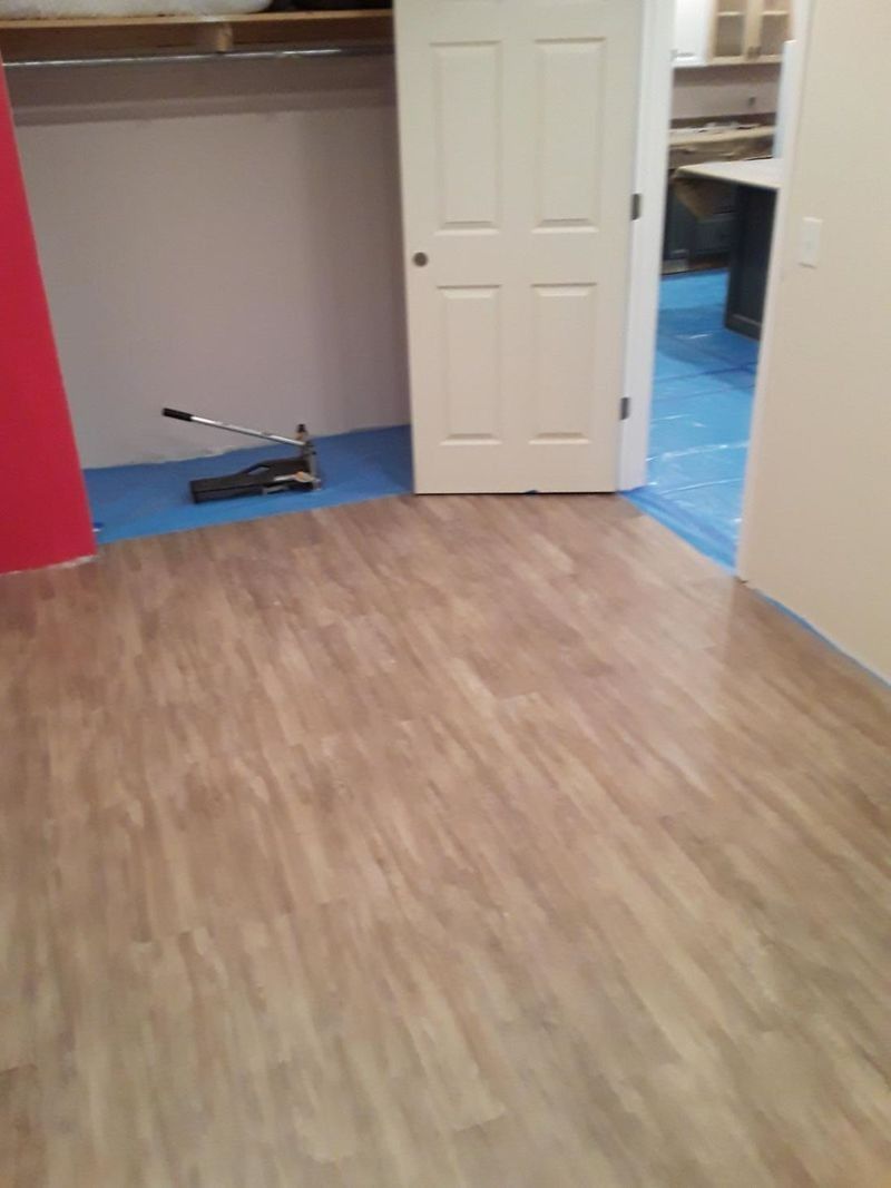 Room with wood-look flooring, door, and unfinished closet. Blue protective covering visible.