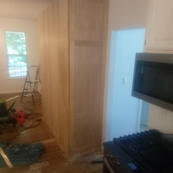 Wooden built-in cabinets in a room; a microwave and stove are visible on the right.