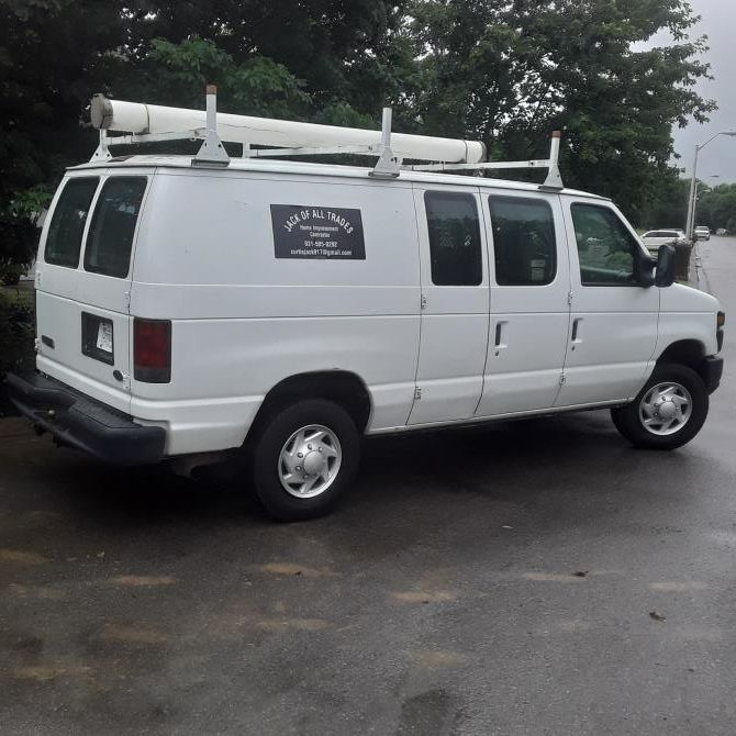 White work van with ladder rack parked on asphalt.