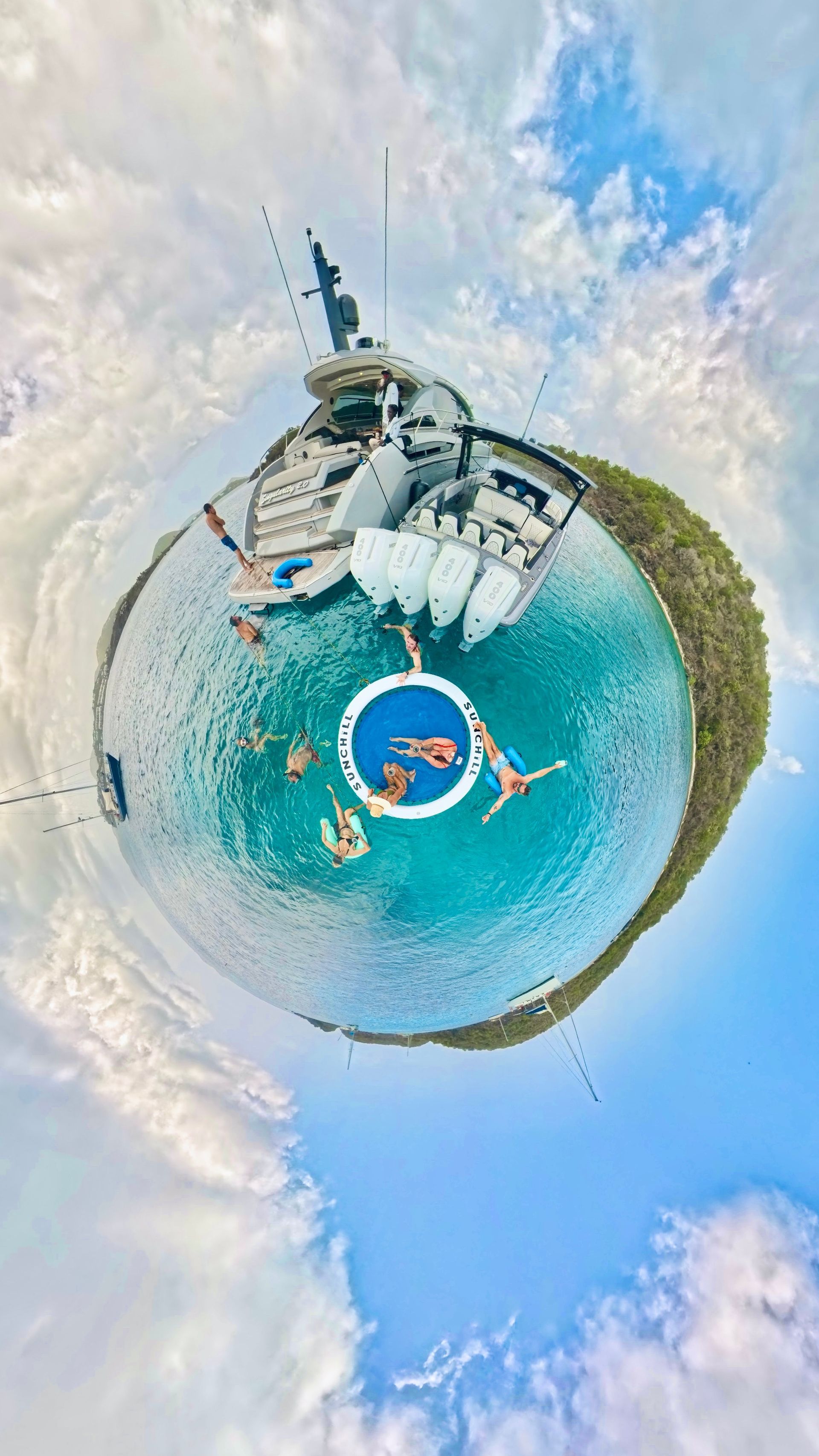 Tiny planet view of yacht, people swimming in turquoise water, blue sky, clouds.