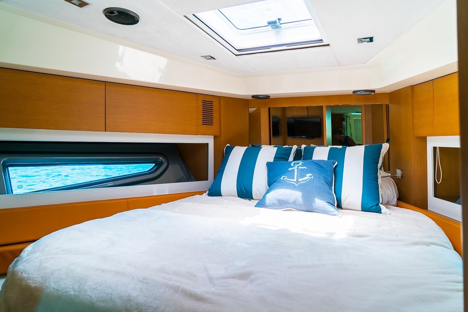 Bedroom on a boat with a bed, porthole, and striped pillows.