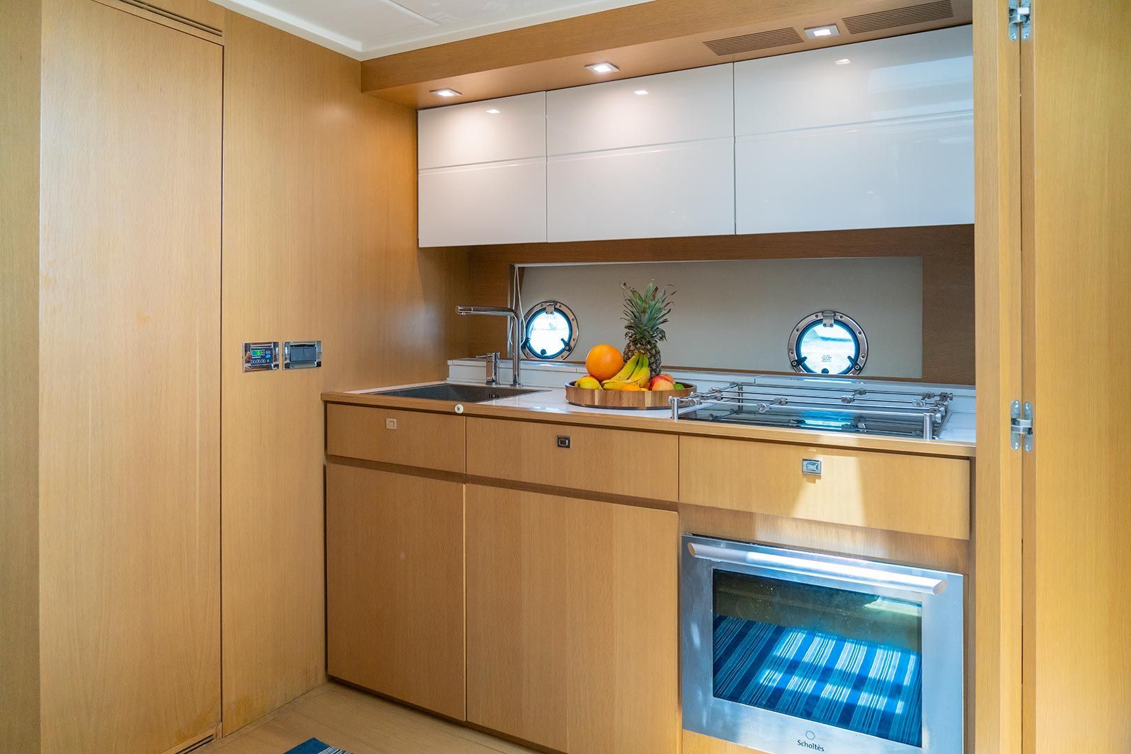 Small boat galley with wooden cabinets, countertop, sink, stove, and a microwave.