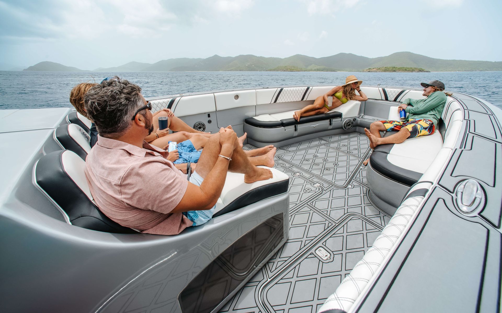 People relaxing on a boat at sea; the boat has white and gray cushioned seating.