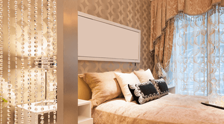 Bedroom decorated in beige and cream, with voile curtains at the large bedside window