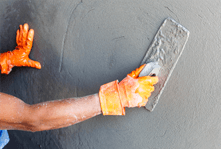 Orange-gloved hands plastering a white wall