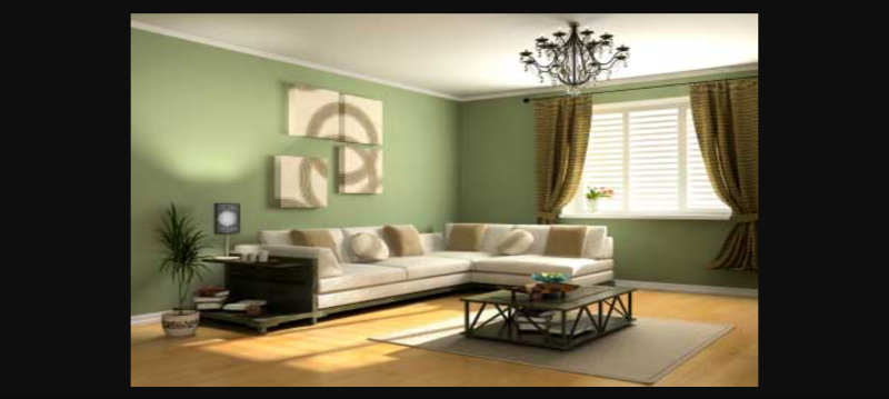A cream L shaped corner sofa against a sage green wall, in a room with a central square coffee table on a beige rug