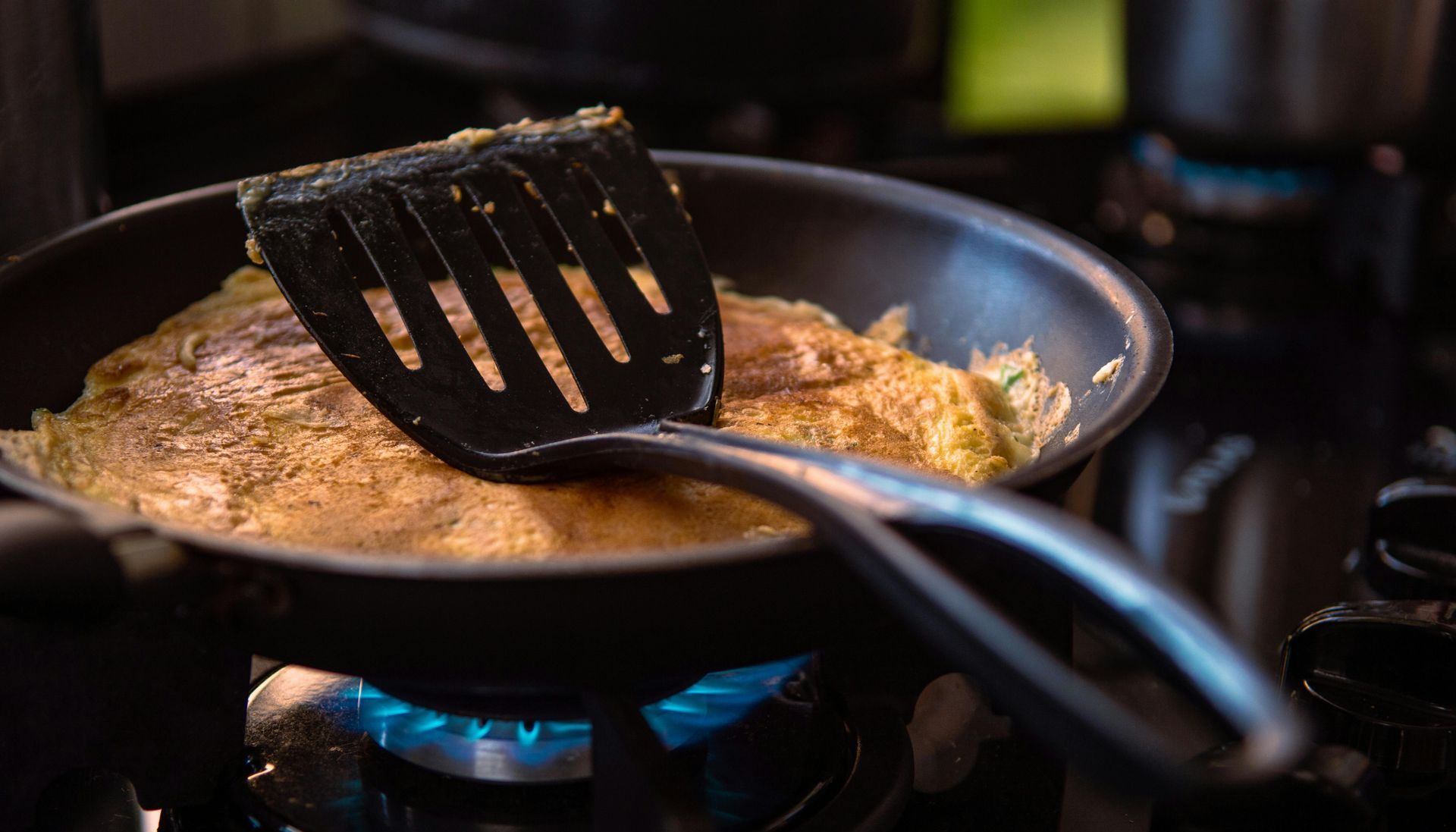 A spatula is being used to stir food in a frying pan on a stove.