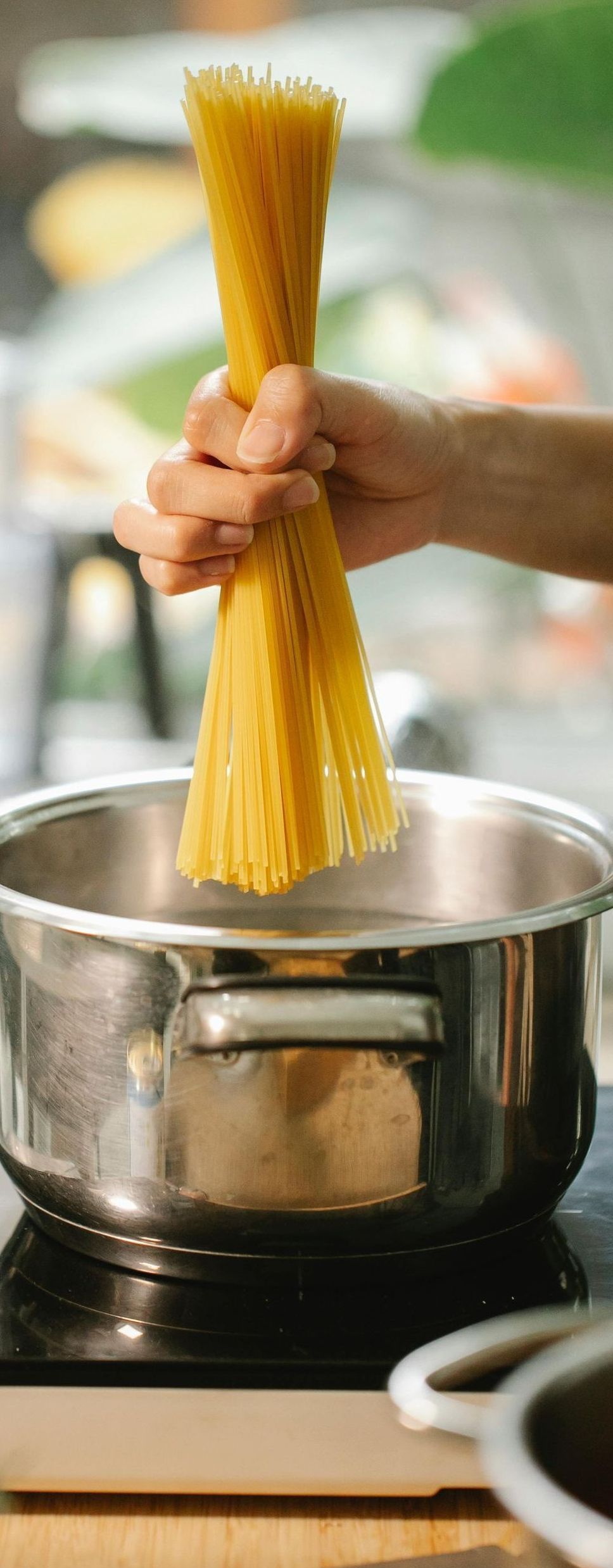 A person is putting spaghetti into a pot of water.