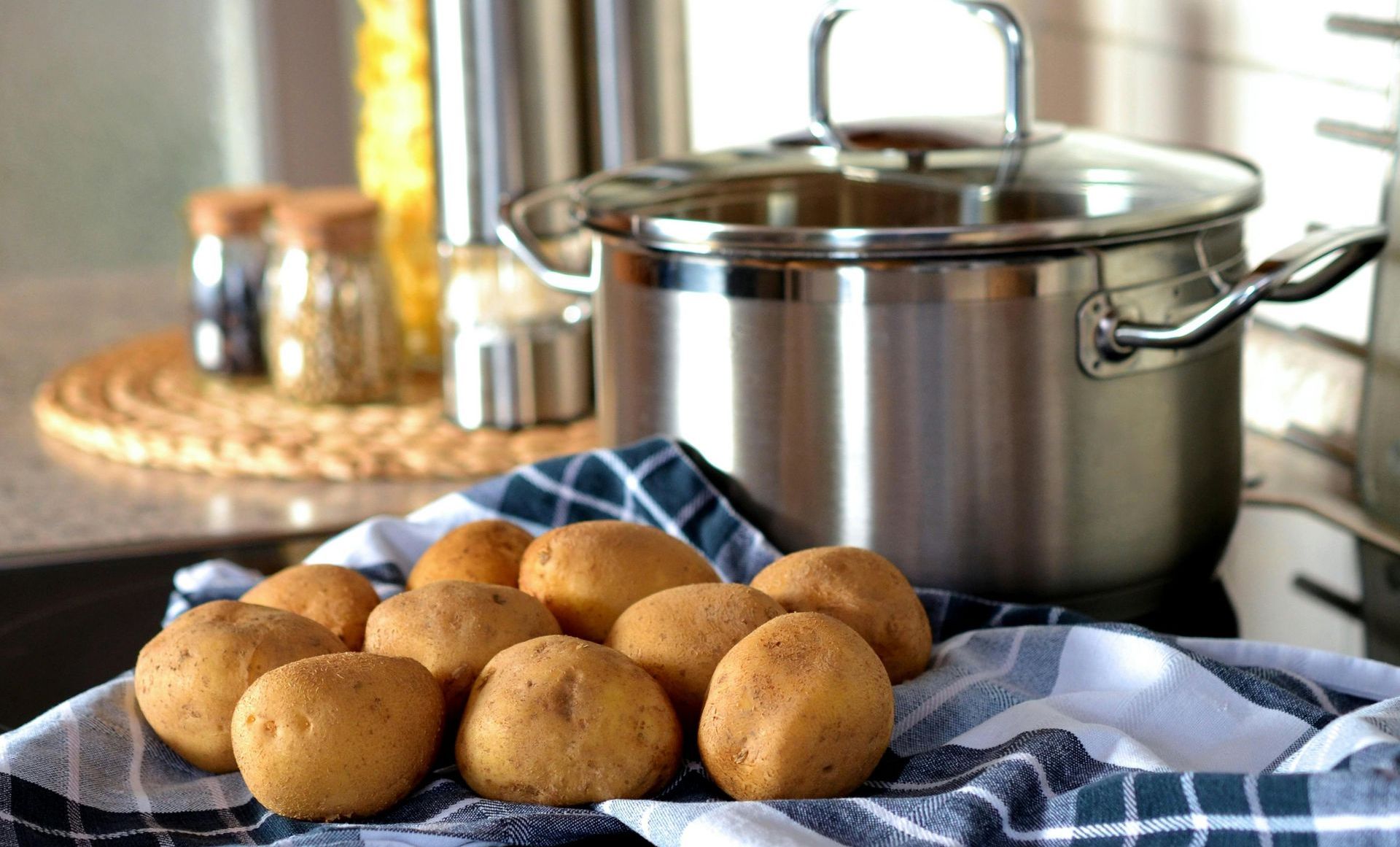 Potatoes are sitting on a towel next to a pot.