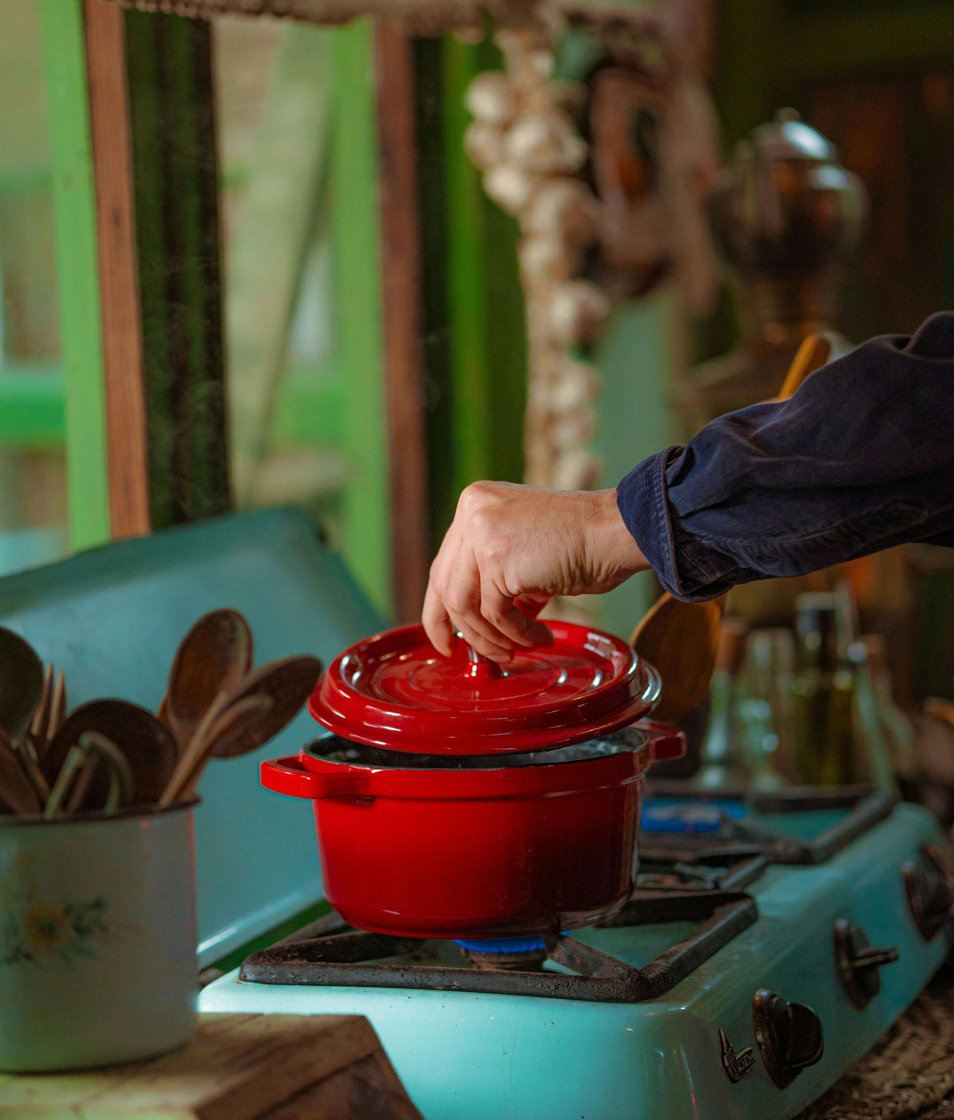 A person is putting a red pot on a stove.