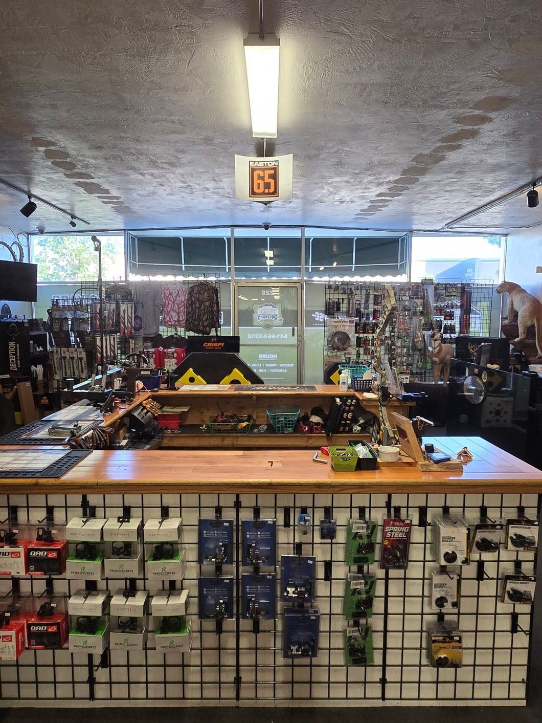 People gathered in an indoor shooting range with targets and firearm stands.