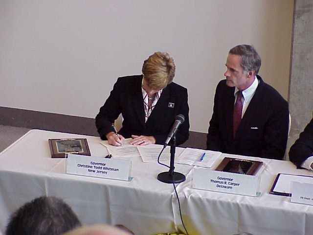 New Jersey Governor Christie Todd Witman signs the Resolution on the Protection of the Delaware River Basin as Delaware Governor Tom Carper looks on at a 1999 Delaware River Basin Commission ceremony.