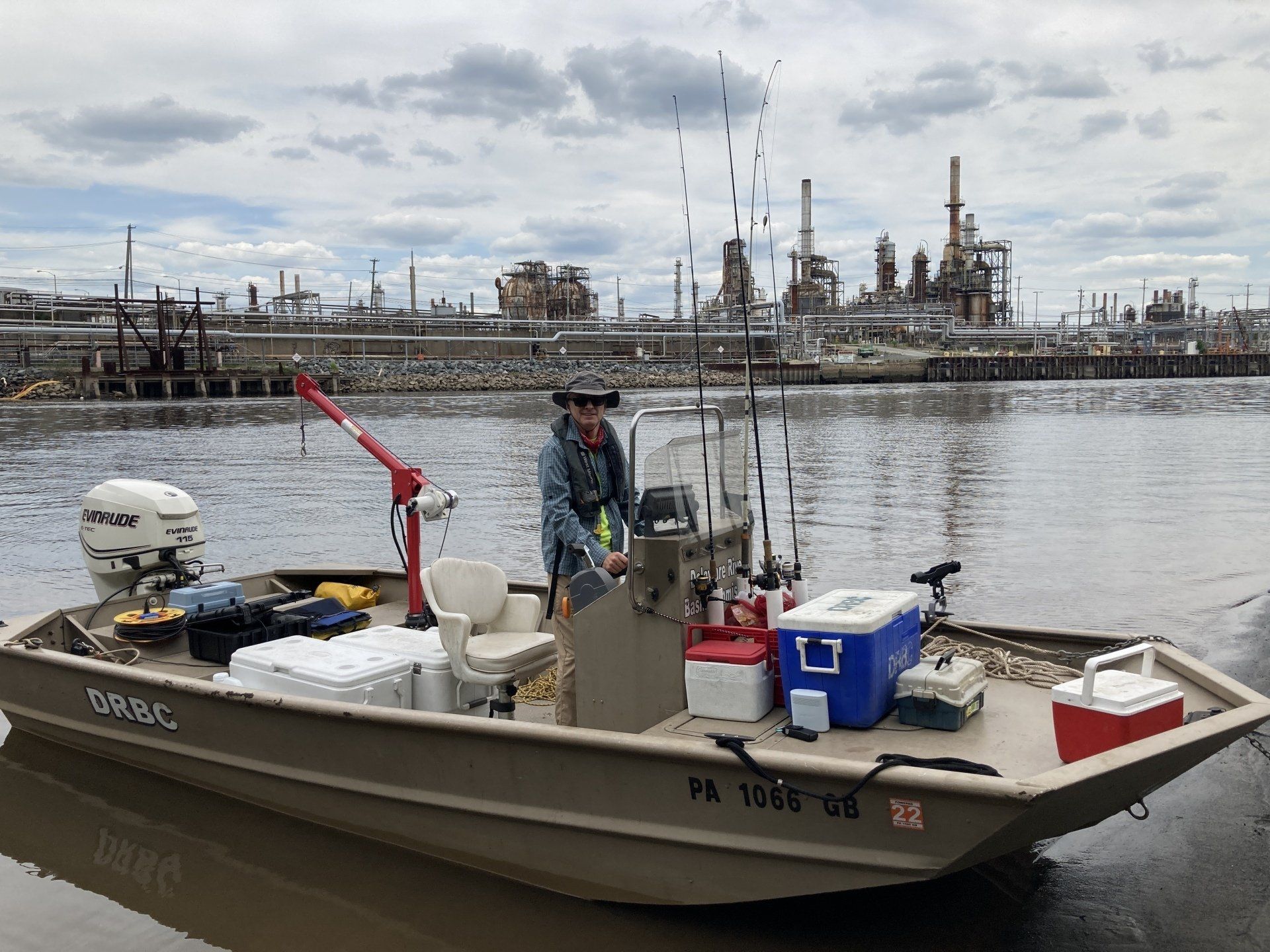 The DRBC staff poses onboard the agency's boat loaded with sampling equipment in front of a Philadelphia oil refinery.