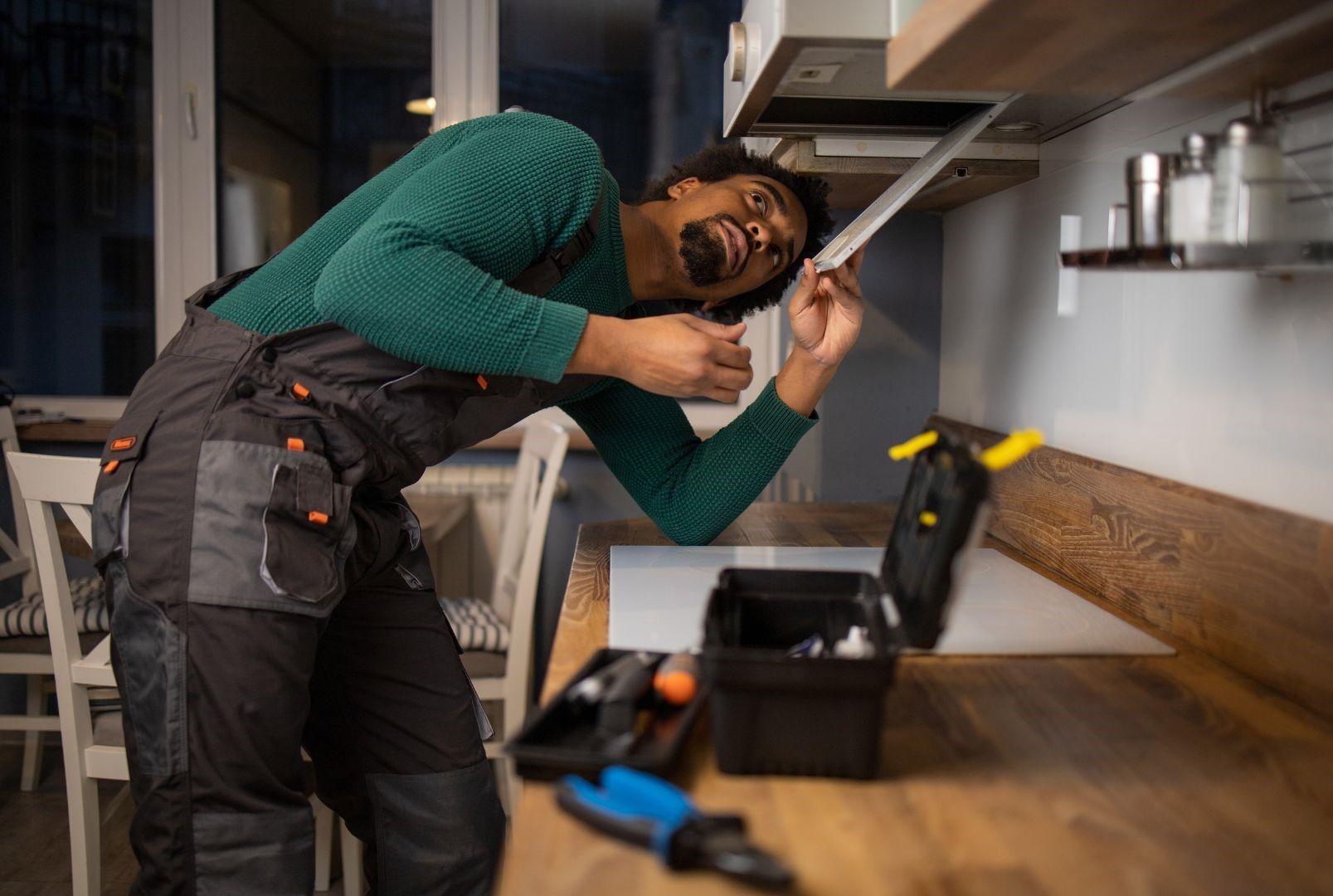 A man is fixing a stove in a kitchen.