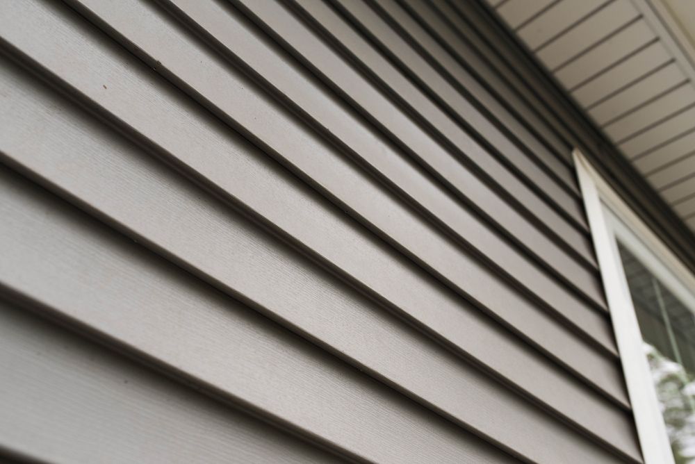 A close up of a gray siding on a house with a window.