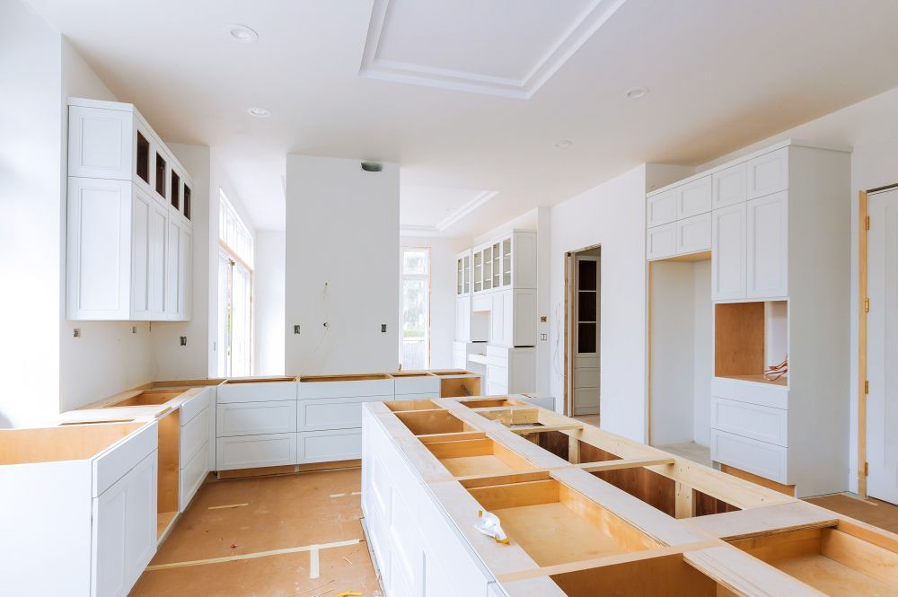 A kitchen under construction with white cabinets and wooden counter tops.