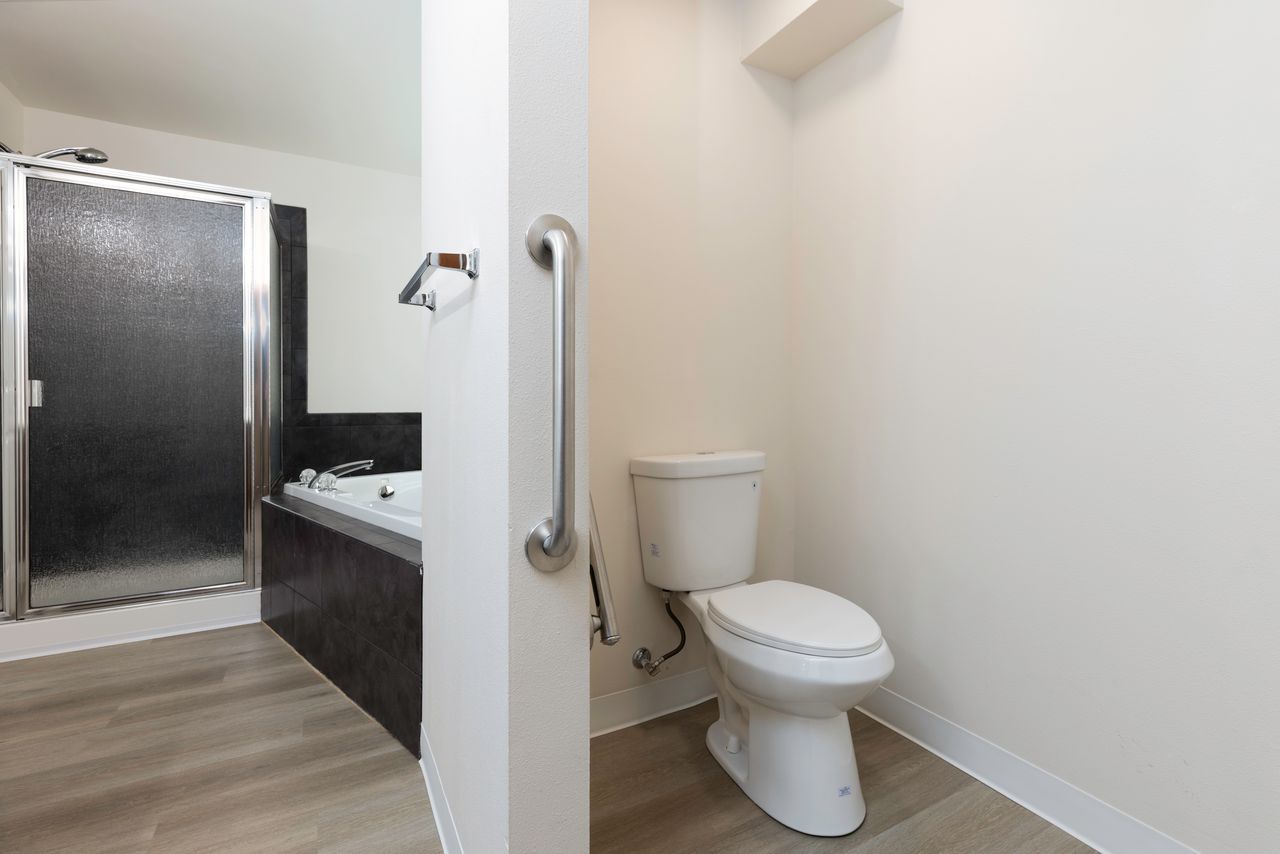 Small bathroom with toilet, dark vanity, sink, and glass shower door