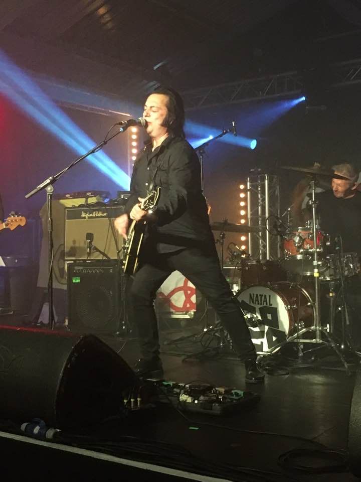 A man is playing a guitar and singing into a microphone on a stage.