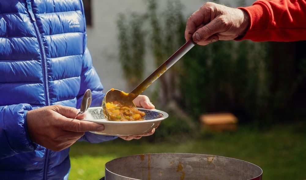 A person is giving a plate of soup to another person.