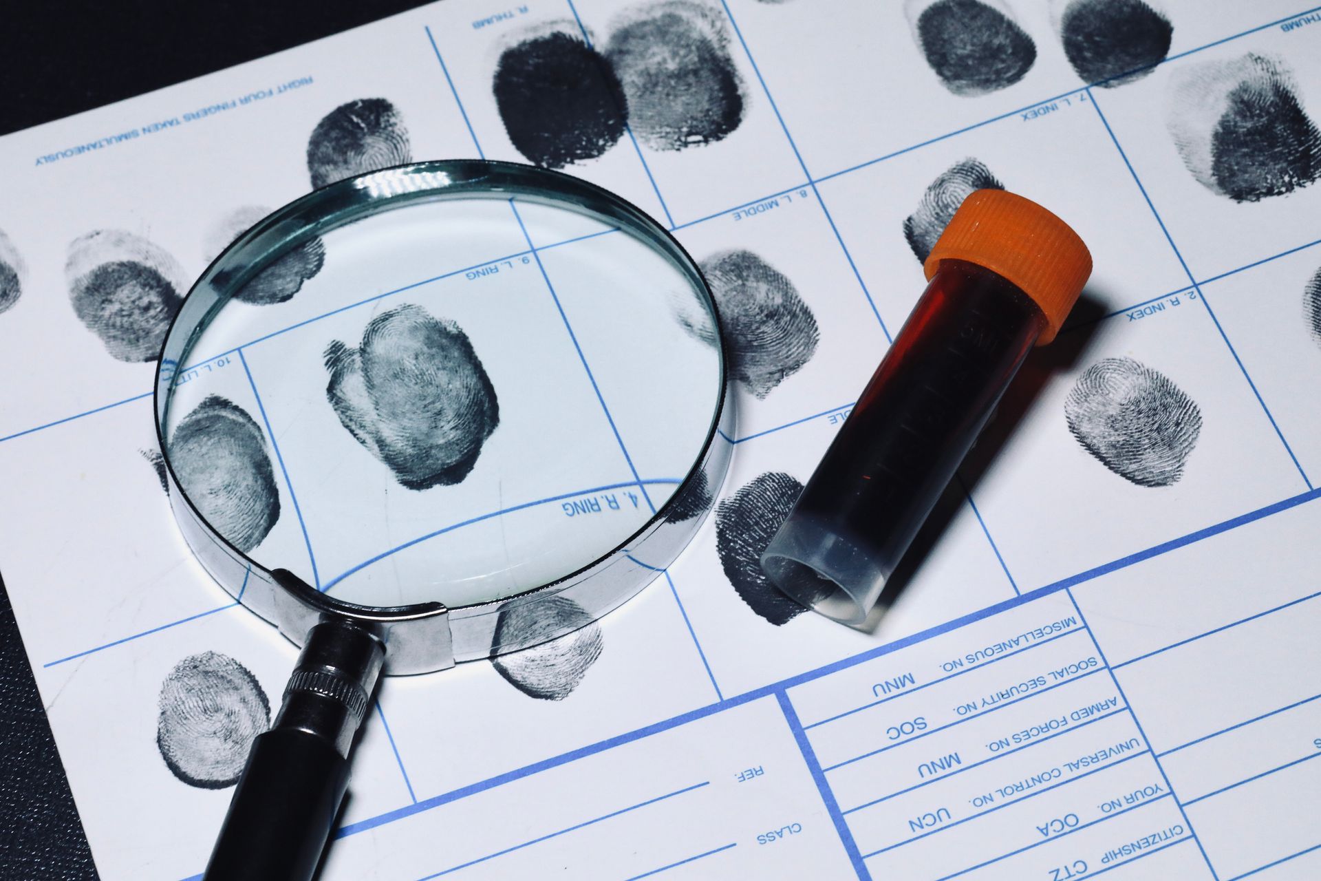 A magnifying glass is sitting on top of a fingerprint sheet