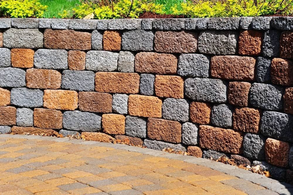 A Brick Wall With A Brick Patio In Front Of It — Baker & Co. Landscape Construction In Gulliver, QLD