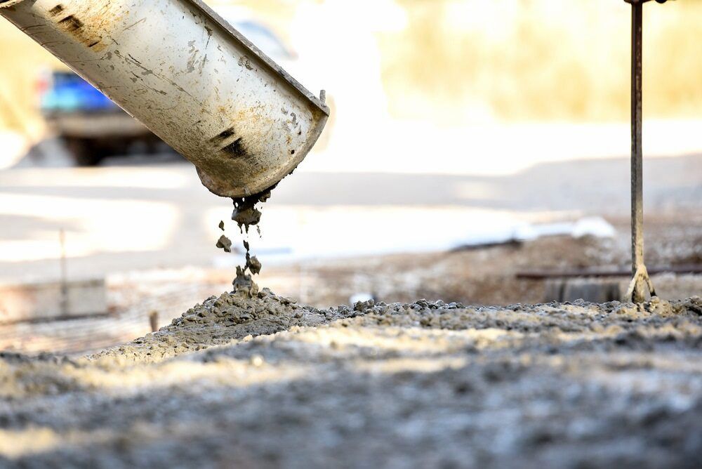 A Close Up Of A Person Pouring Concrete On A Sidewalk — Baker & Co. Landscape Construction In Gulliver, QLD