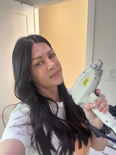 A woman is taking a selfie while holding a machine.