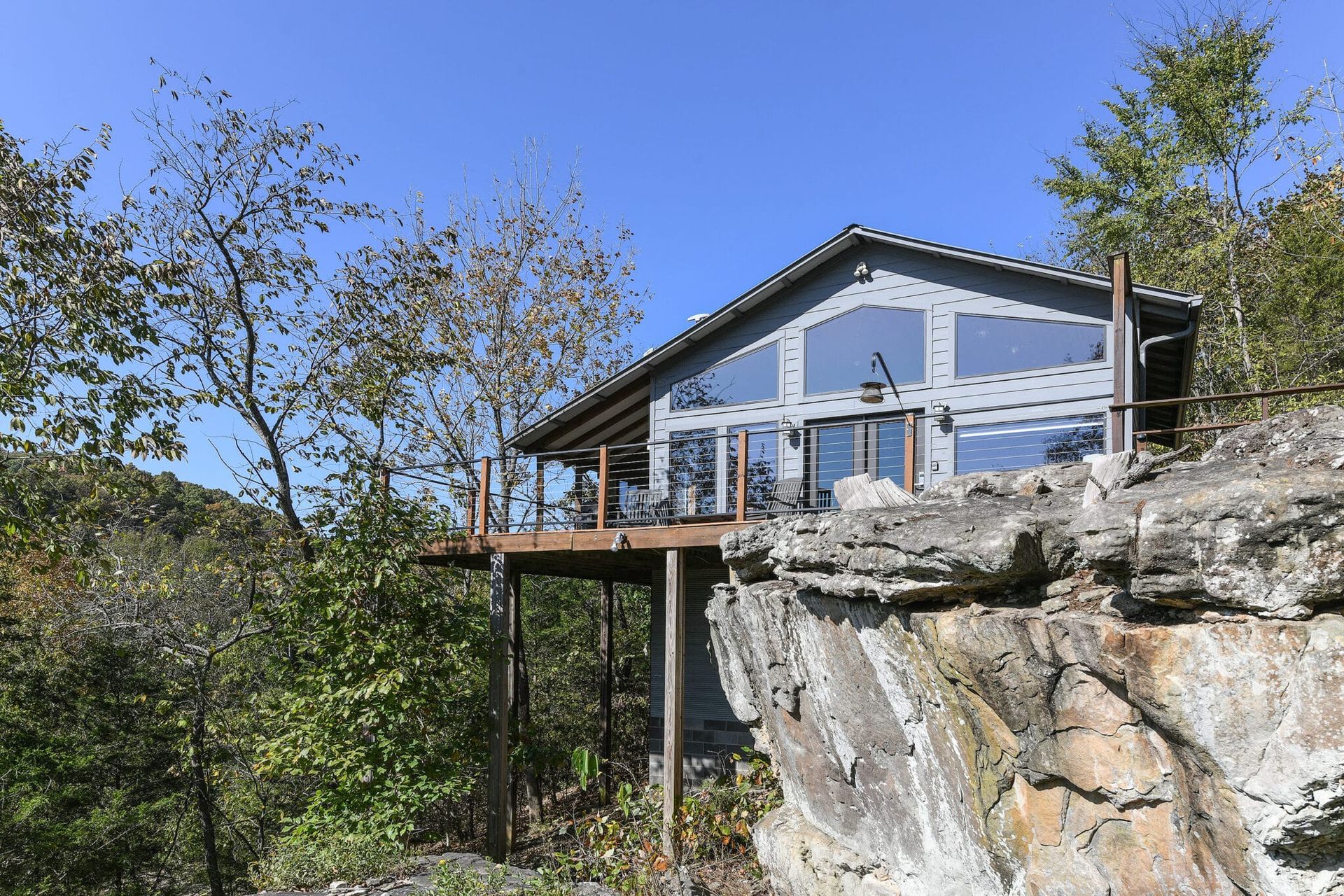 A house is sitting on top of a rocky cliff surrounded by trees.